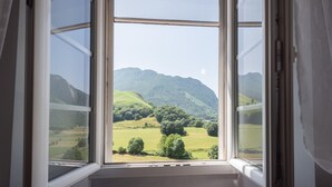 Ein Zimmer mit einem großen Fenster und Blick auf eine grüne Landschaft mit Hügeln.