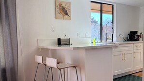 A modern kitchen with a central island, bar stools, a window with a view, and a coffee maker on the counter. - Peaceful Three Rivers Retreat Near Sequoia National Park with EV charger, AC (Three Rivers)