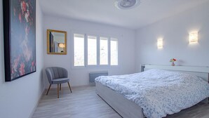 Een slaapkamer met een bed, een stoel, een spiegel en een raam.