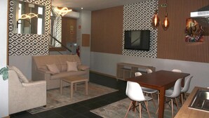 Un interior moderno con sofá, mesa de comedor, sillas, televisor y paredes con estampado.