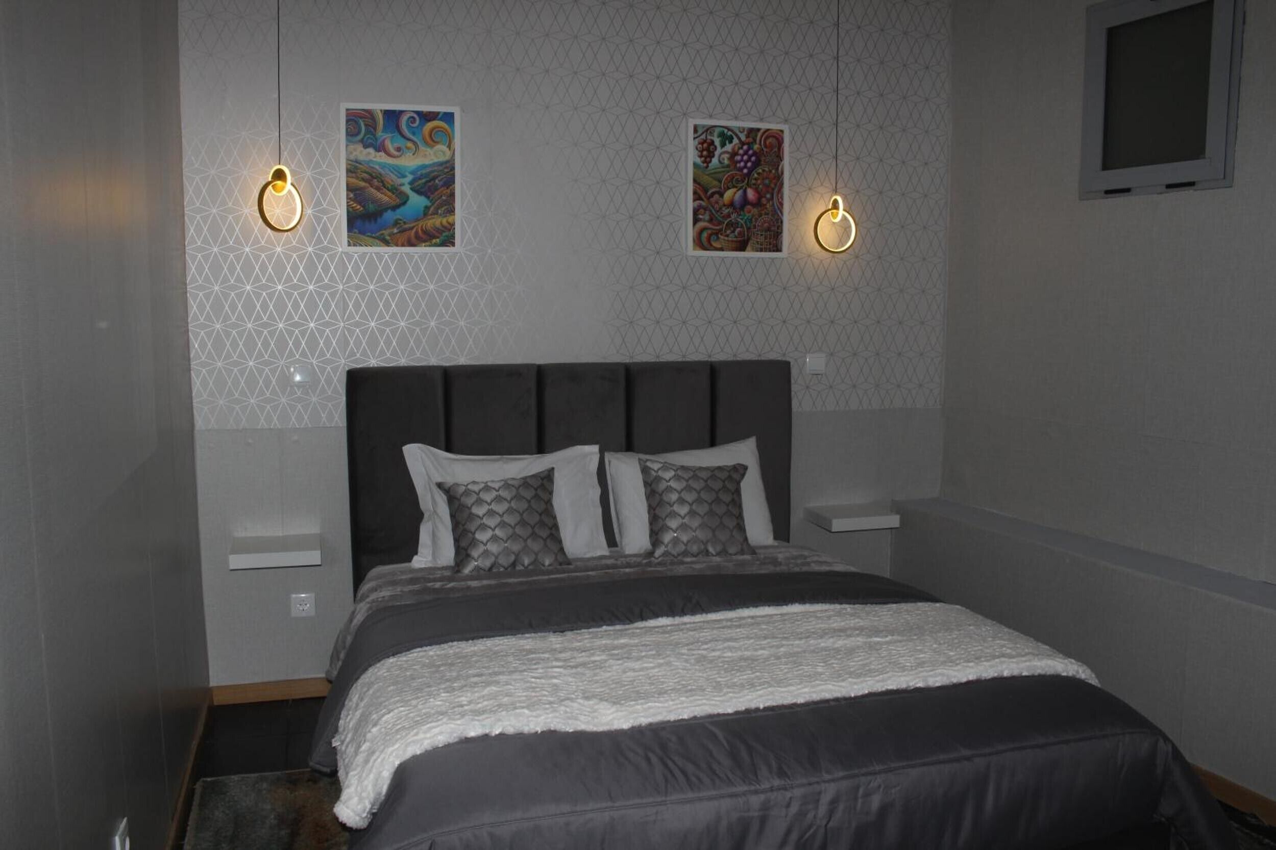 Un dormitorio con cama, dos lámparas de pared y dos obras de arte enmarcadas.