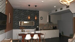 Una cocina moderna con comedor, que cuenta con una salpicadera de mármol, iluminación colgante y un microondas.