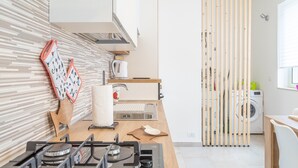 A modern kitchen with a gas stove, wooden countertop, and a washing machine in the background.