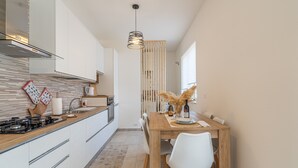 A modern kitchen with white cabinets, a wooden countertop, and a dining area with a wooden table and white chairs.