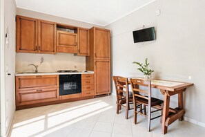 A kitchen with wooden cabinets, a built-in dishwasher, a dining table with chairs, and a wall-mounted TV.