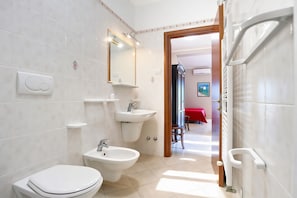 A modern bathroom with a toilet, bidet, and sink.