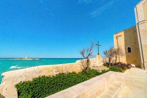 Une vue sur la côte, avec un phare, un mur de pierre et un bâtiment surmonté d’une croix.