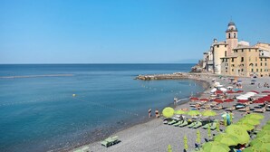 Ein Strand mit Sonnenschirmen, ein Gebäude mit einem Turm und ein klarer Himmel.