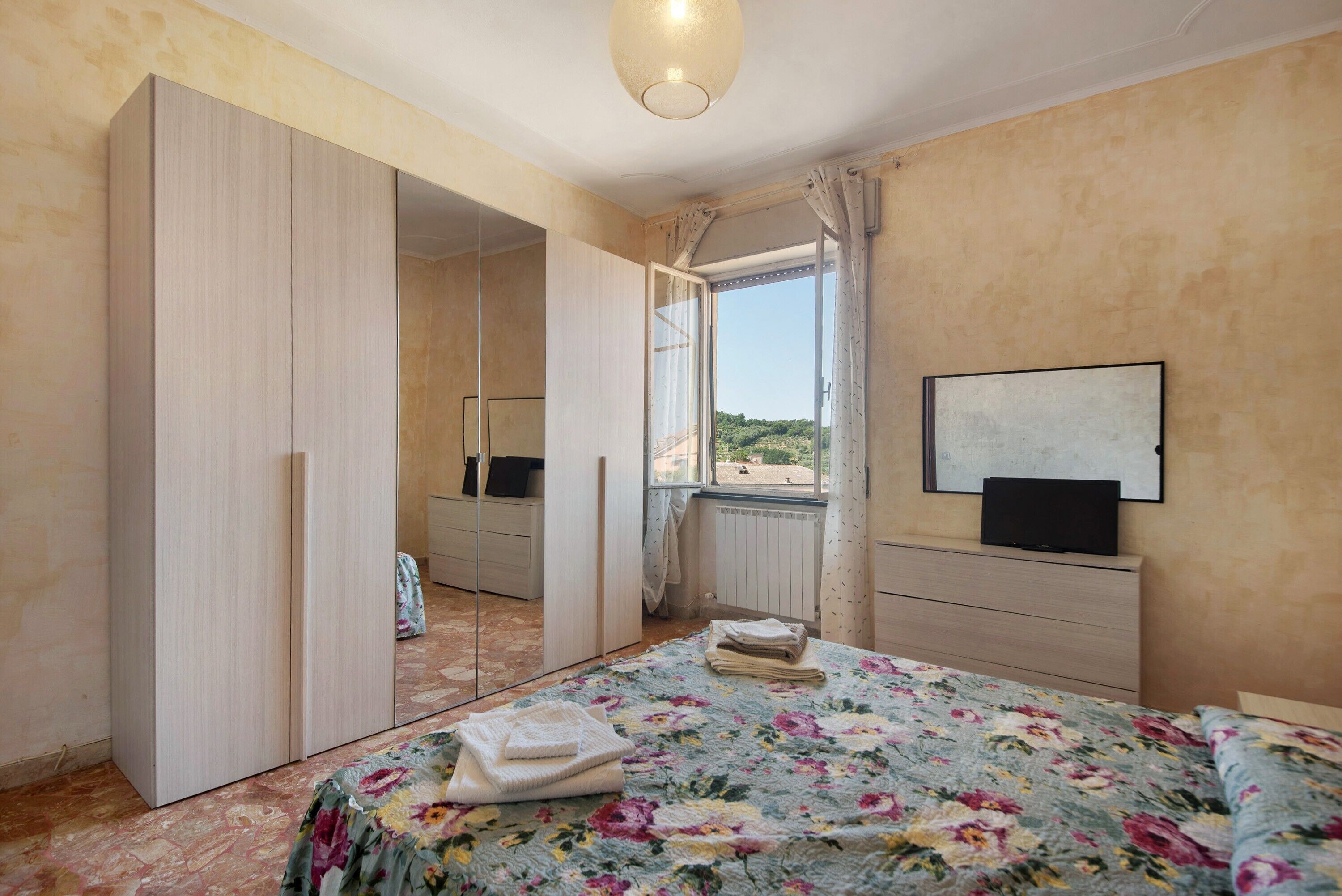 Une chambre à coucher avec un lit, une télévision, une armoire et une fenêtre donnant sur un beau paysage.
