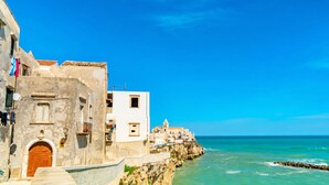 A coastal building with a stone facade, a wooden door, and a balcony with clothes hanging. - Casa Limoncino - Villa Mapa with Sea View, Wi-Fi and Air Conditioning (Unknown)