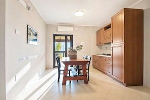 A kitchen with wooden cabinets, a dining table with chairs, and a window with a view of greenery. - Casa Limoncino - Villa Mapa with Sea View, Wi-Fi and Air Conditioning (Unknown)