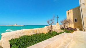 A coastal view with a lighthouse, a stone wall, and a building with a cross. - Casa Limoncino - Villa Mapa with Sea View, Wi-Fi and Air Conditioning (Unknown)