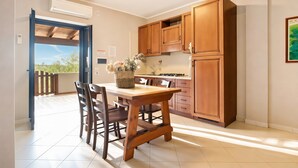 A kitchen with wooden cabinets, a dining table with chairs, and a view to the outside. - Casa Limoncino - Villa Mapa with Sea View, Wi-Fi and Air Conditioning (Unknown)