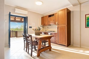 A kitchen with wooden cabinets, a dining table with chairs, and a view to the outside.