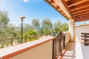 A balcony with a view of olive trees and a clear sky.