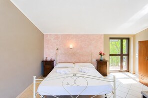 A bedroom with a bed, nightstands, a vase with flowers, and a view through a door. - Fiorone Apartment with Sea View, Wi-Fi and Air Conditioning (Vieste)