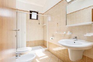 A bathroom with a shower, toilet, sink, and a mirror.