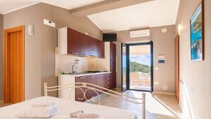 Une chambre d’hôtel comprenant un lit, une salle de bain, une kitchenette et un balcon avec vue.