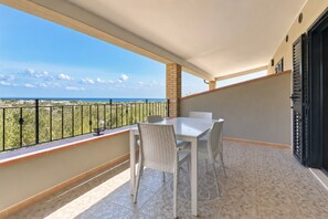 Ein Balkon mit Tisch und Stühlen, Blick auf das Meer und ein Fliesenboden.