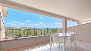 Un balcon avec une table et des chaises, une vue sur la mer et un sol carrelé.