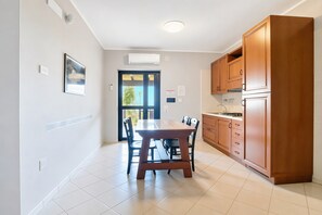 Una cocina moderna con armarios de madera, una mesa de comedor con sillas y vistas por la puerta.