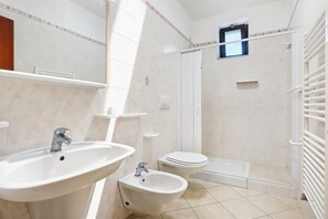 A bathroom with a sink, bidet, toilet, and shower.