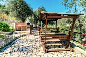A stone-paved patio with a wooden pergola and a barbecue area. - Casa Tasso - Villa Mapa with Sea View, Wi-Fi, and Air Conditioning (Vieste)