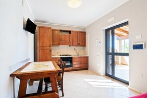 A kitchen with wooden cabinets, a dining table, and a TV mounted on the wall.