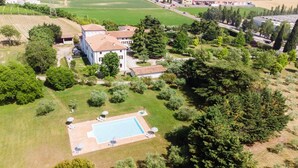 A large estate with a swimming pool, surrounded by lush greenery and a spacious lawn.