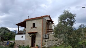 Un edificio de piedra con techo de tejas, un pequeño porche y una planta en maceta.
