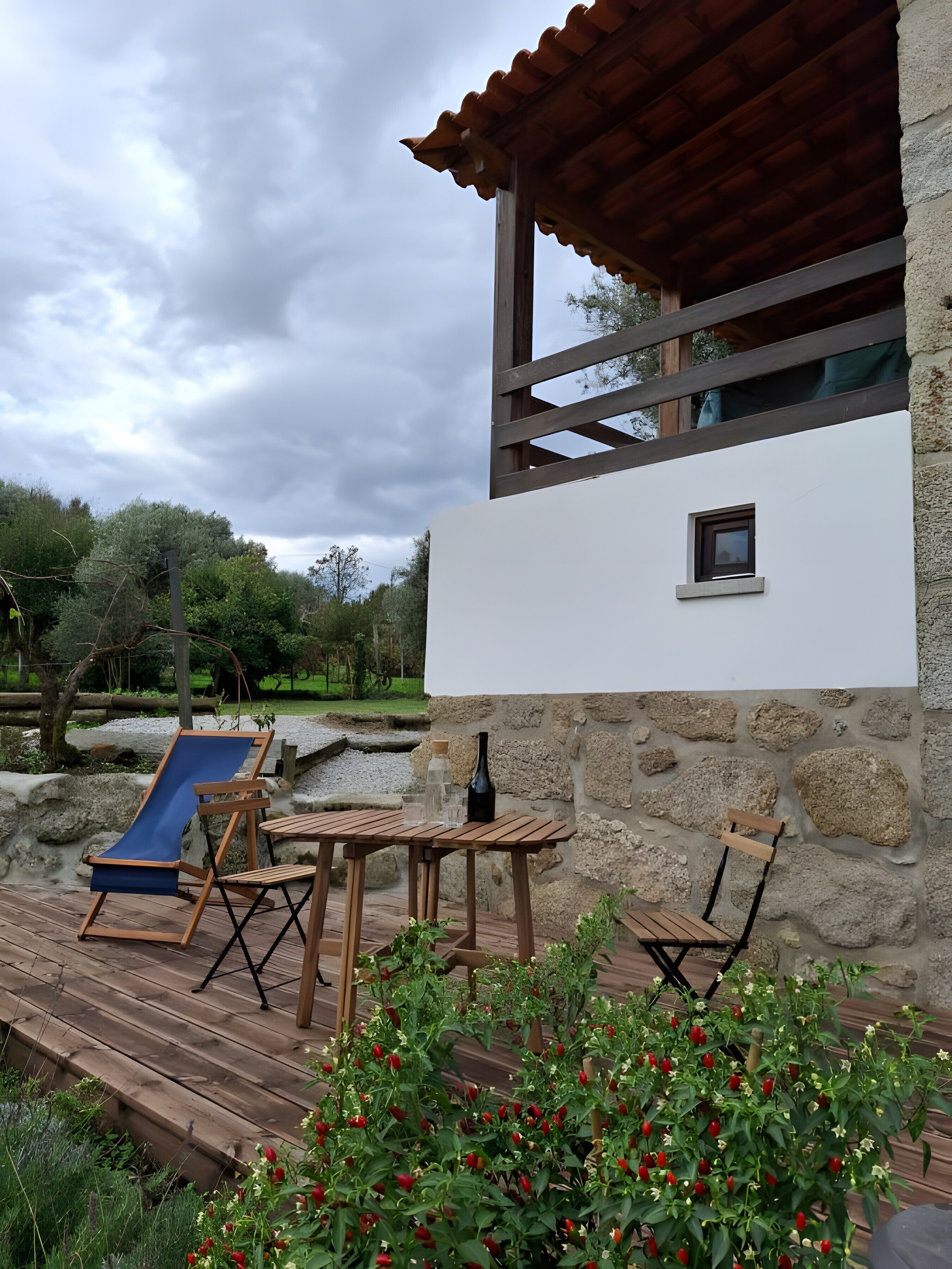 A wooden deck with a pool, a stone wall, and a small window.