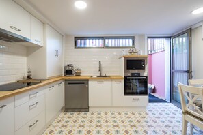 A compact kitchen with white cabinets, a dishwasher, a microwave, and an oven.