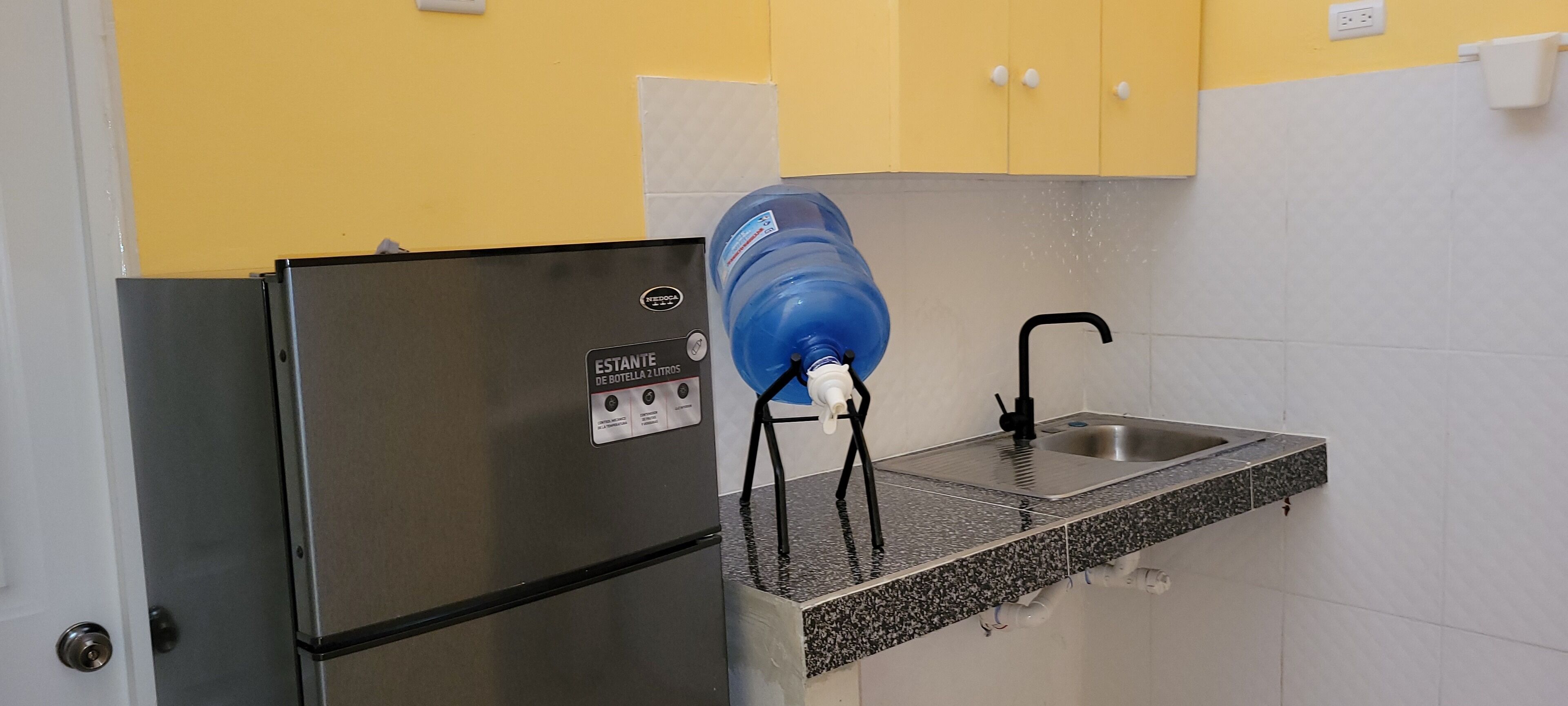 Una cocina con un refrigerador de acero inoxidable, un dispensador de agua y un lavabo.