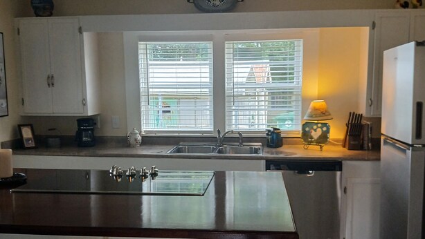 A kitchen with a central island, white cabinets, a ceiling fan, and a window with blinds. - Charming 1-bedroom cottage in Holly Pond with AC, WiFi (Holly Pond)