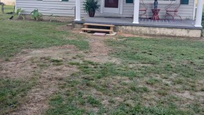 A single-story house with a front porch, a small garden, and a clear sky. - Charming 1-bedroom cottage in Holly Pond with AC, WiFi (Holly Pond)