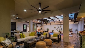 A spacious living area with a high ceiling fan, comfortable seating, and a view of a swimming pool. - Privacy, Luxury and Relaxation, Heated Pool & Spa - Villa Courtyard - Roelens (Cape Coral)