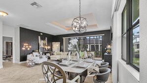 A spacious dining area with a large table set for six, surrounded by modern chairs. - Privacy, Luxury and Relaxation, Heated Pool & Spa - Villa Courtyard - Roelens (Cape Coral)