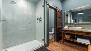 Une salle de bain moderne avec une douche à parois de verre, un meuble-lavabo en bois et un grand miroir.