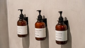Trois flacons de produits de soins pour la peau sont fixés au mur.