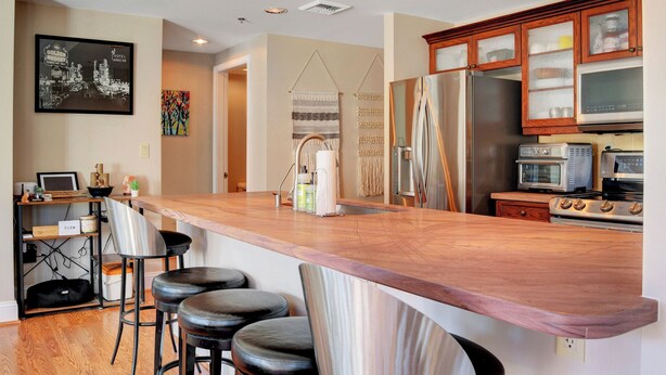 A modern kitchen with a wooden countertop, stainless steel appliances, and a bar area with stools. - Desert Oasis Apartment at Viera Resort (Henderson)