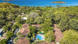 A resort with multiple bungalow-style buildings, a swimming pool, and a view of the ocean and islands. - Stylish 1-bedroom condo with workspace, walk to everything + massages on us! (Potrero)