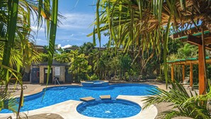 A swimming pool with a hot tub, surrounded by palm trees and lounge chairs. - Stylish 1-bedroom condo with workspace, walk to everything + massages on us! (Potrero)