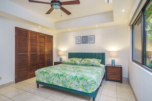 A bedroom with a bed, wooden closets, a ceiling fan, and framed pictures on the wall. - Stylish 1-bedroom condo with workspace, walk to everything + massages on us! (Potrero)