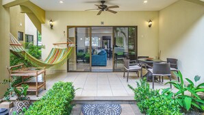 A covered patio with a hammock, outdoor furniture, and potted plants. - Stylish 1-bedroom condo with workspace, walk to everything + massages on us! (Potrero)