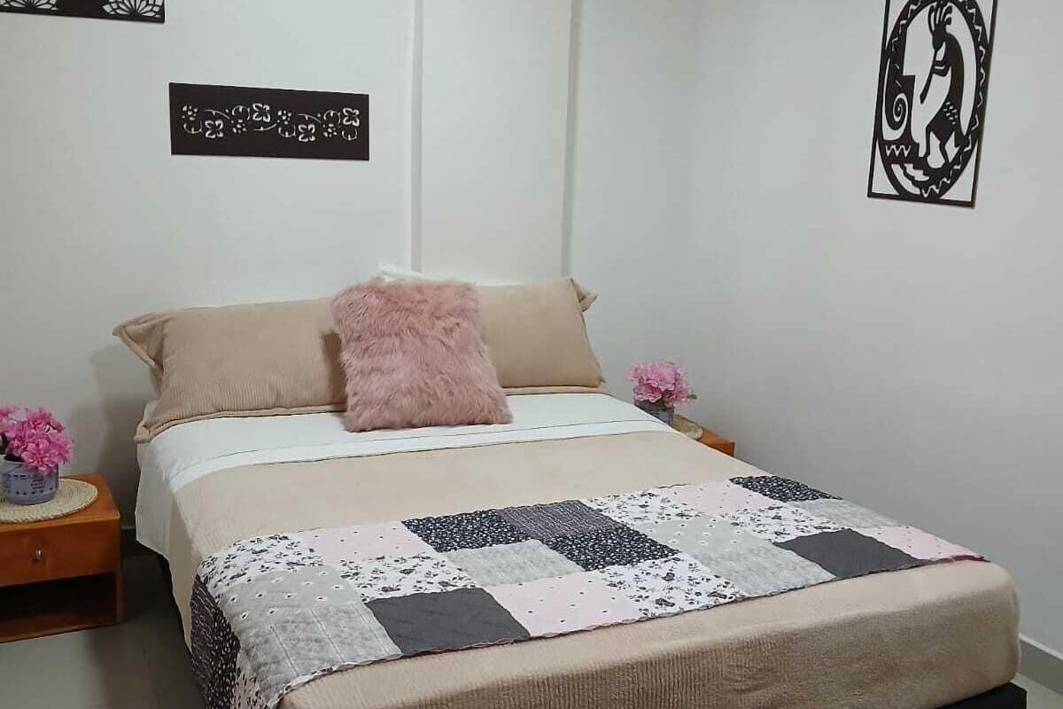 Un dormitorio con cama, mesita de noche, un adorno en la pared y una alfombra.