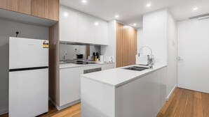 A modern kitchen with white cabinetry, a built-in oven, a sink, and a wooden floor.