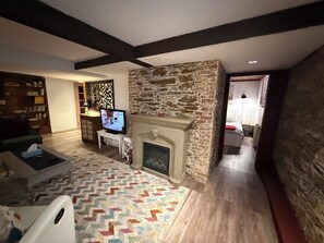 A living room with a fireplace, a television, a bookshelf, and a patterned rug. - Stylish unit in Victorian house located on South Park Street. Private Garden. (Halifax)