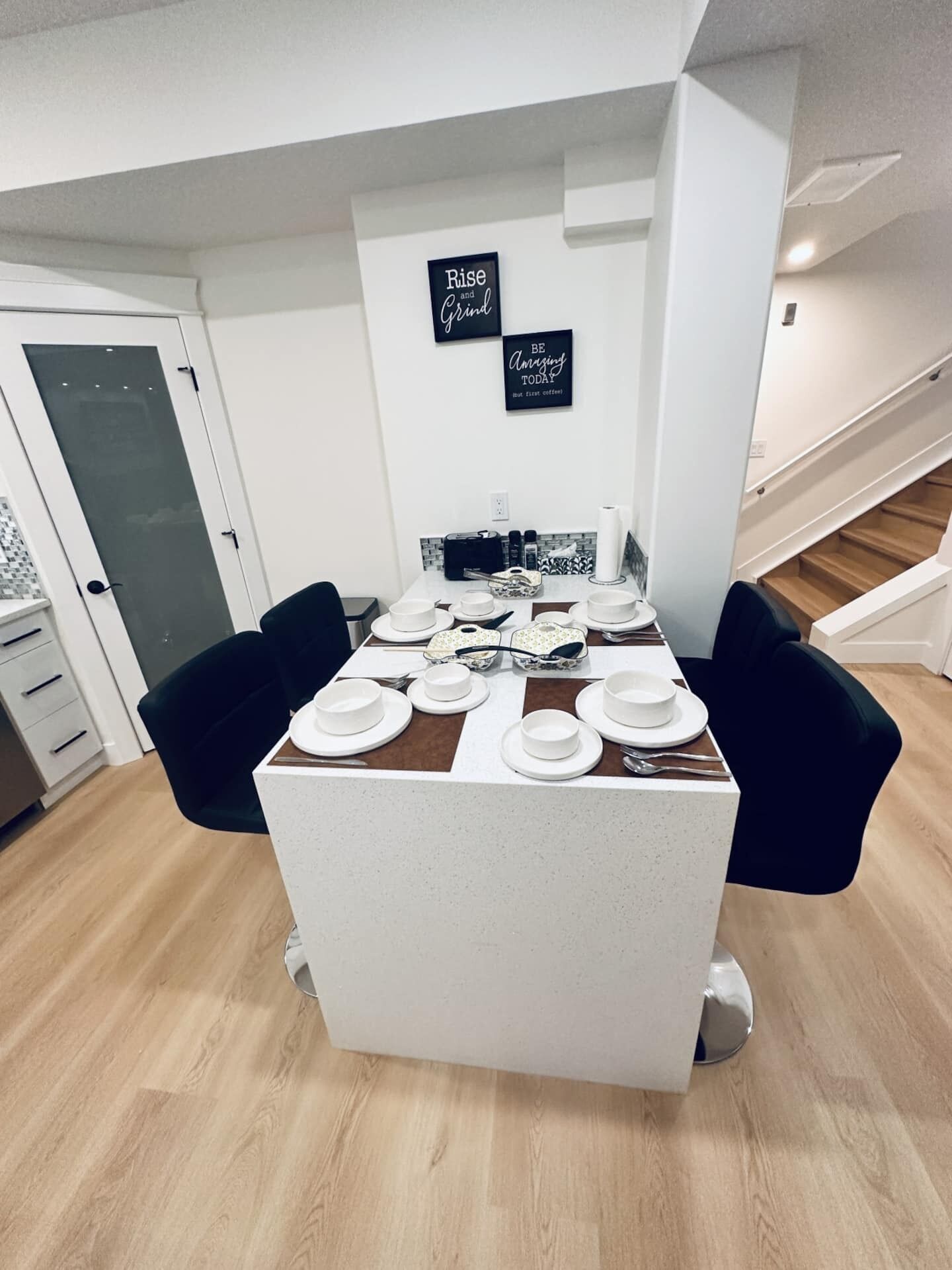 Un espace repas moderne avec une table centrale pouvant accueillir quatre personnes, entourée de chaises noires. Deux panneaux avec des citations inspirantes sont fixés au mur.