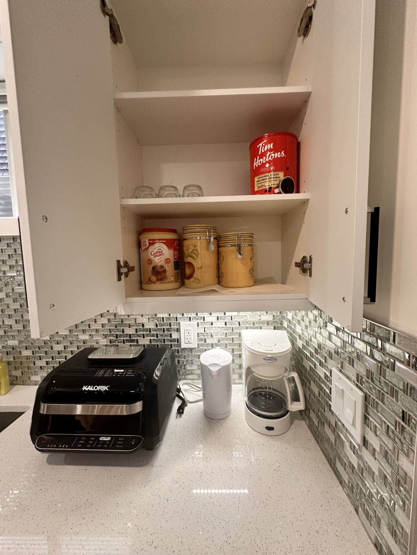 A kitchen with a coffee maker, a kettle, and storage containers.