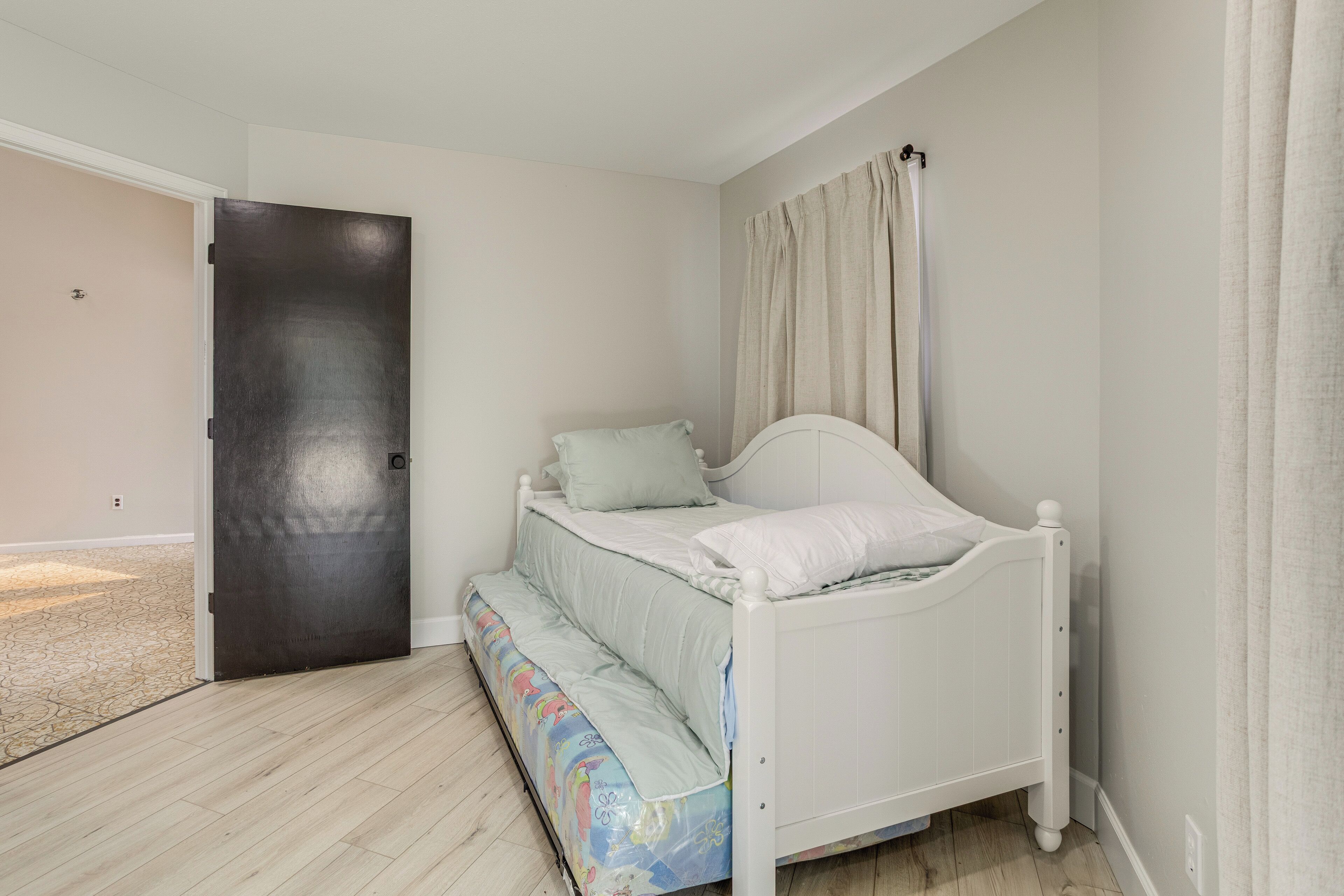 Een slaapkamer met een bed, een deur en uitzicht op buiten.